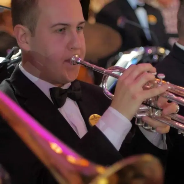 Harrisson Ball in a tuxedo playing trumpet in a big band section