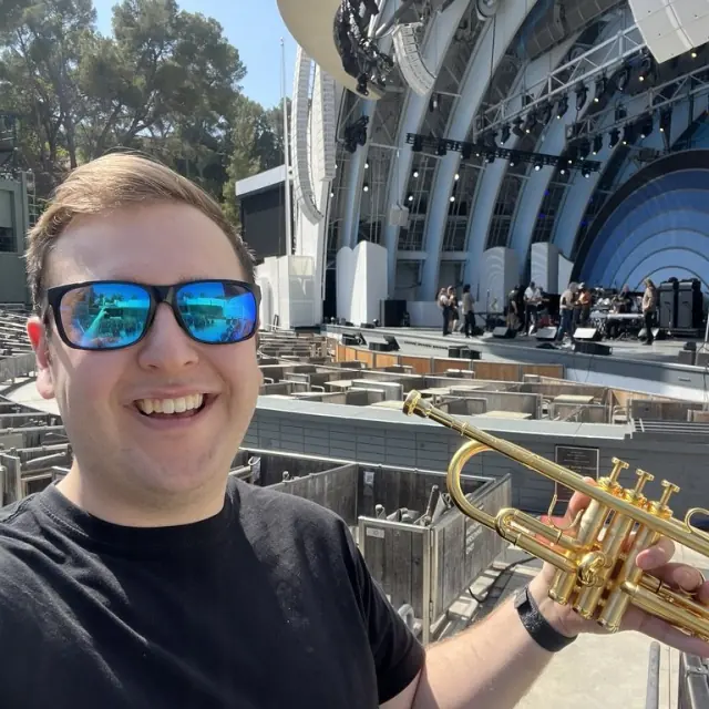 Harrisson Ball with a gold trumpet at the Hollywood Bowl, the band shell behind him