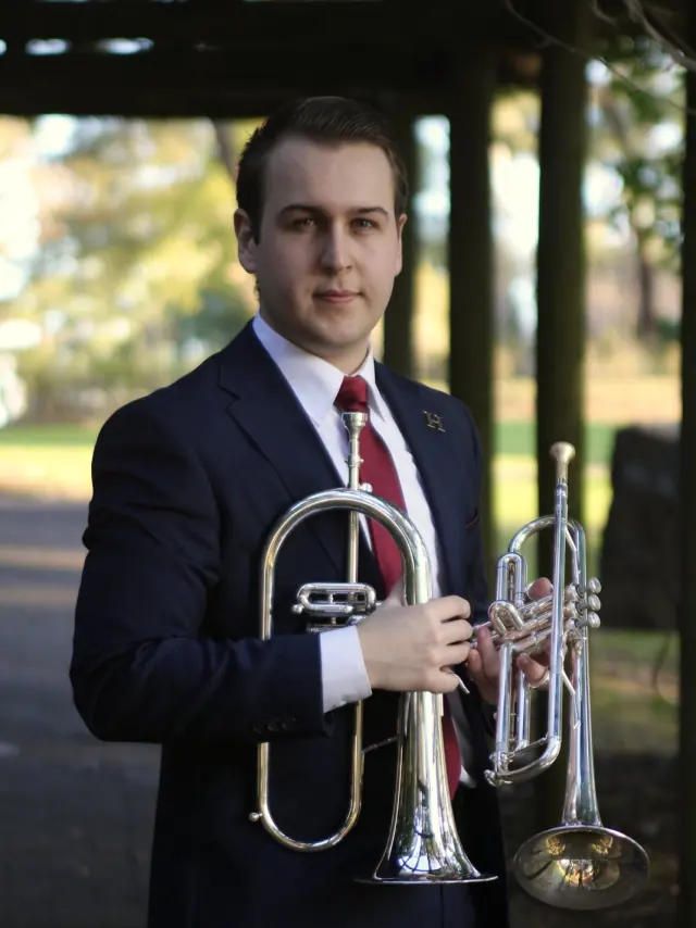 Press portrait of Harrisson Ball holding a flugelhorn and a trumpet