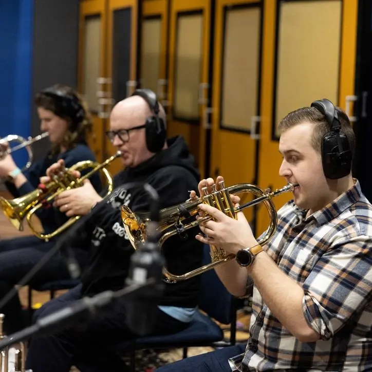 Harrisson Ball recording in a trumpet section, three players in headphones