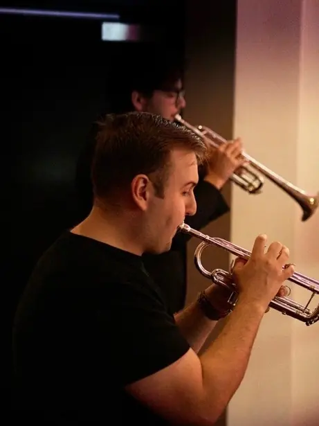 Harrisson Ball playing a silver trumpet with a brass section lined up behind him