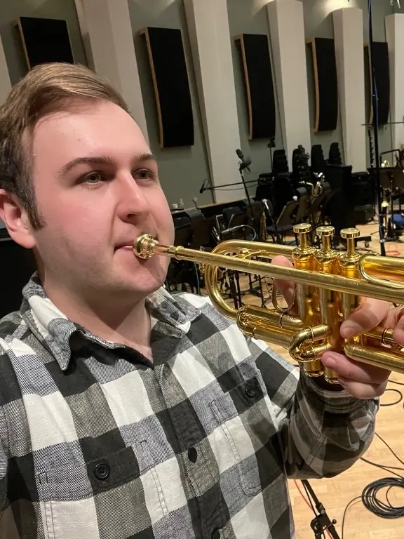Harrisson Ball playing a gold trumpet on a scoring stage