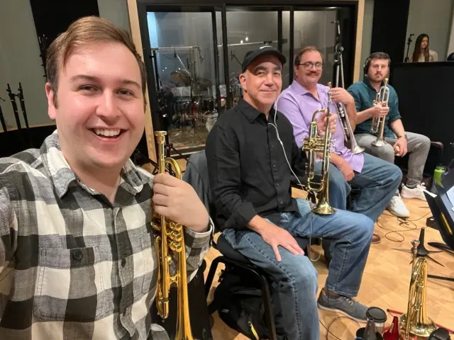 Harrisson Ball in front of a seated brass section at a recording session